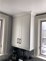 First set of white shaker upper cabinets installed above countertop, two doors, crown molding