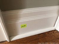 Close-up of painted baseboard trim with decorative groove and approx 8 inches tall profile.