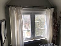 Window view with mounted curtain rod and drapery panels