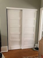 Front view of two white sliding doors mounted on track