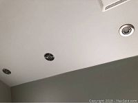 Wide angle photo showing four recessed silver-tone pot lights installed in the ceiling.