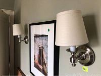 View of both sconces mounted on wall showing brushed nickel finish and fabric shades.