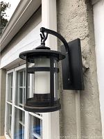 Front view of the black metal and glass lantern mounted on stucco wall