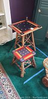 Two Americana-themed wooden end tables with star and stripe painted tops and rustic branch legs seen from an angle.