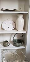 Photo of five pottery pieces on shelf, including vase, dishes, and cup.