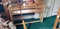 Photo showing the wooden side sofa table with several baskets and a broom placed on and around it, demonstrating its size and appearance.