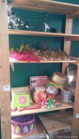 Shelf with various items including plastic grape clusters, vases, a deck of playing cards, pillow, and photo album.