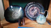 Full view of pottery bowl, plate, pitcher, and salt and pepper shakers on wooden shelf