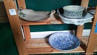 Wooden shelving unit displaying two ceramic trays and a large bowl, showing organization and context for the lot.