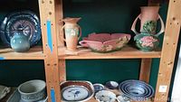 Shelf with two large Roseville vases and pink floral bowl along with various dishware