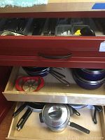 Drawers open showing blue pots, pans, cast iron cookware along with apple slicer