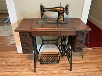 Front view of the wooden sewing machine table with Singer treadle base and drawers