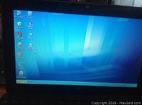 Laptop powered on, showing Windows XP desktop with icons for My Computer, Recycle Bin, Adobe Reader, and Internet Explorer.