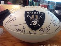 Photo of white football with Raiders logo and autograph featuring 'Just Win Baby!' and dedication 'To Tobias'.