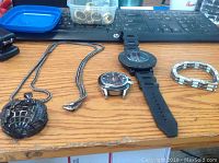 Full lot on desk showing two watches, a necklace with black globe pendant, and a silver tone bracelet.