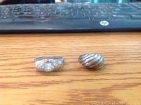 Photo showing two silver rings side by side on wooden surface in front of keyboard.