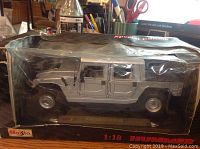 Silver Maisto Hummer H1 scale model displayed inside factory plastic box showing full side profile and detailing of the model.