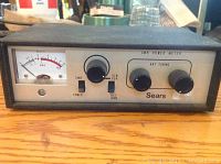 Front view of the vintage Sears SWR power meter showing analog needle gauge, tuning knobs, power switch, and Sears branding on metal panel.