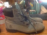 Side view of the men's Timberland boots showing grey upper material, black padded collar, laces, and Timberland logo on side.