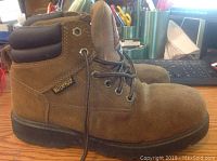 Side profile of brown suede Brahma boot with waterproof tag on ankle collar and black rubber sole, showing overall condition and design.