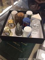 Top angled view of the 9 thimbles in the presentation box showing a variety of materials and decorative designs.