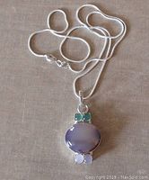 Full view of sterling silver necklace showing pendant with oval center quartz, two green gemstones on top and two pink rose quartz stones below, and the snake chain with lobster clasp.