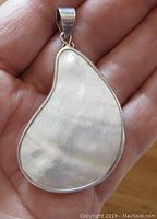 Front side of the pendant showing iridescent mother of pearl with pink and green hues in a freeform shape with sterling silver trim.