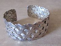 Angled side view showing woven motif and open cuff design