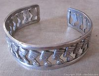 Side view of vintage sterling silver bangle with repetitive Nefertiti head motifs forming an openwork design.