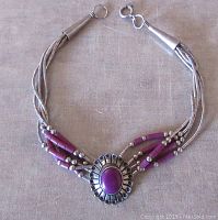 Front view of vintage sterling silver bracelet showing multiple silver strands intertwined with purple beads and a central oval purple stone in decorative setting.