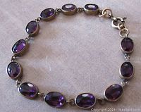 Close-up of the antique Victorian bracelet showing amethyst glass stones in brass bezels on a neutral background.
