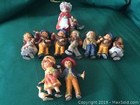 View of the 10 Bradford Christmas tree ornaments laid out on green fabric, showing the details and colors of each figure.