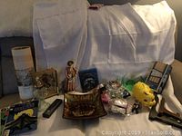 Photo showing a variety of collectibles including comics, piggy bank, figurine, and McDonald's toys laid out on a white backdrop on a couch.