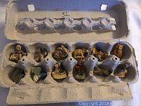 Top-down view of all ten ceramic animal figurines arranged inside an egg carton showing size and storage context.