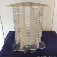 Front angle of vintage clear Lucite CD rack showing vertical CD slots and rounded top and base.