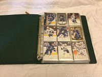 Open green binder displaying 9 hockey cards of Toronto Maple Leafs players in plastic sleeves.
