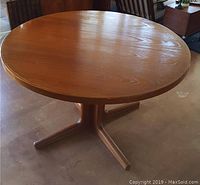 Front view of round teak table with four-star pedestal base