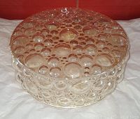 Angled close-up photo showing the amber bubble glass ceiling light shade with various sized bubbles and reflective surface, highlighting the textured design and dome shape.