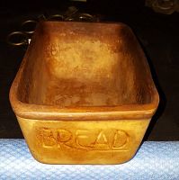 Front view of vintage terracotta bread pan showing interior wear and the word 'BREAD' on one side.