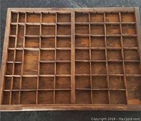 Top view of vintage wooden printers type set tray drawer showing multiple small compartments in a grid layout.