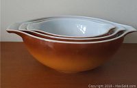 Side view of the set of 3 stacked Pyrex Cinderella mixing bowls showing brown-orange gradient finish and white interiors.