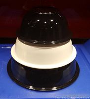 Three Pyrex nesting mixing bowls stacked black-white-black, showing glossy finish and size differences.