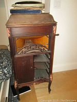 Full front view of dark wood console showing decorative grill opening, missing lower door panel