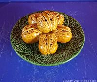 Top view of the green Majolica leaf patterned plate holding seven walnut-shaped salt and pepper shakers.