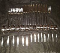 Full set of 30 stainless steel cutlery pieces laid out on brown fabric, showing 10 dinner knives, 5 salad forks, 1 dinner fork, 8 teaspoons, and 6 soup spoons in polished condition.