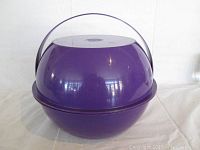 Photo showing purple plastic spherical picnic ball with handle, front view