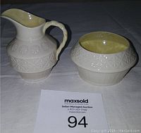Side view of cream jug and sugar bowl showing embossed patterns and yellow interior glaze