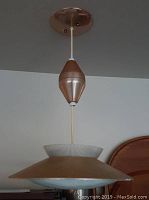 Photo showing the fixture extended down from ceiling mount with mid century modern UFO shaped shade and wood-toned middle component.