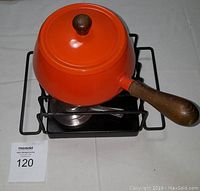 Top view of the bright orange fondue pot on the burner tray with one burner inside