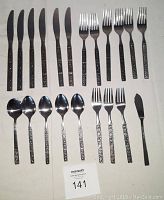 Full view of 21-piece cutlery set including 6 dinner knives, 6 dinner forks, 3 salad forks, 4 teaspoons, butter knife, and sugar spoon arranged on a white surface.